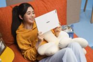 Девушка держит белый планшет Asus Pad с OLED-экраном на диване