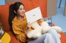 Девушка держит белый планшет Asus Pad с OLED-экраном на диване