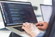 Программист работает на ноутбуке с открытым редактором кода