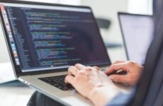 Программист работает на ноутбуке с открытым редактором кода