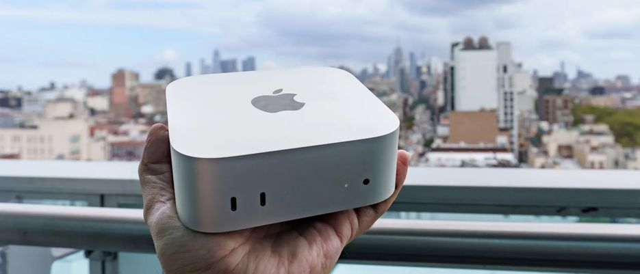 Mac mini M6 в ладони на фоне городской панорамы